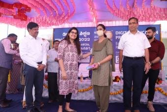 A high standard school student receives the tab from the dignitaries present in the event