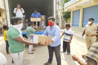 A delighted old woman receives the grocery kit with a smile.